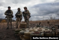 Бойцы спецподразделения по разминированию Нацполиции Украины стоят возле обезвреженных противотанковых мин