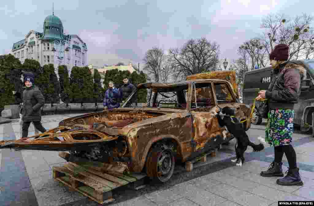 Людзі глядзяць на разбураныя машыны, якія прывезьлі валянтэры з перадавой пад Бахмутам, каб паказаць наступствы вайны і сабраць сродкі на новыя машыны для жаўнераў, ва ўкраінскім Львове.