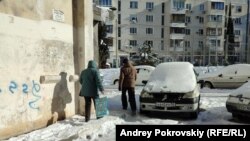 Пожилые люди идут во двор по скользкому тротуару