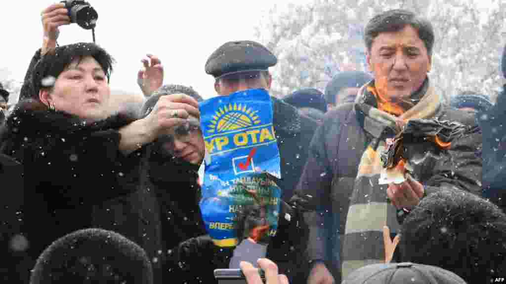 Болат Әбілев (оң жақтан бірінші) оппозиция жетекшілерімен бірге парламент сайлауы нәтижесіне наразылық ретінде &quot;Нұр Отан&quot; партиясының плакатын өртеп тұр. Алматы, 17 қаңтар 2012 жыл.