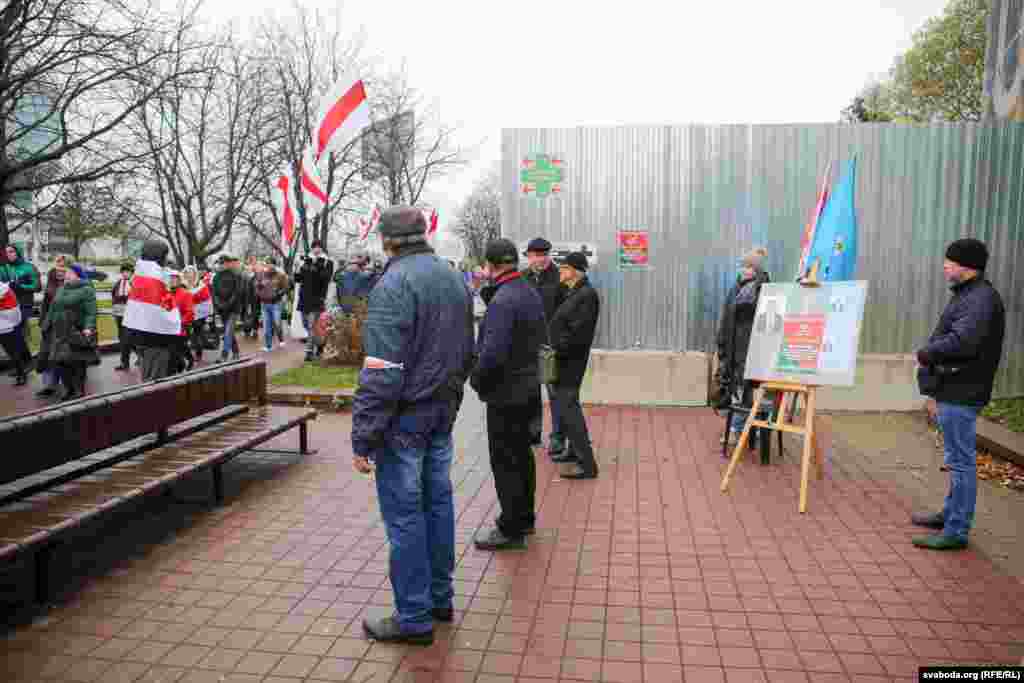 Арганізатары і супрацоўнікі міліцыі абараняюць пікет ў падтрымку кандыдата ў дэпутаты з чырвона-зялёным сьцягам ад магчымых правакацый