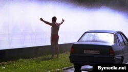 Belarus -- The young man refresh himself and his car in a cloud of spray from the fountain