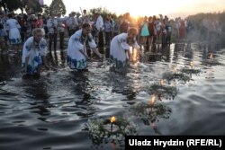 Дзяўчаты запальваюць сьвечкі на вянках і пускаюць на ваду. Архіўнае фота, 2018 году