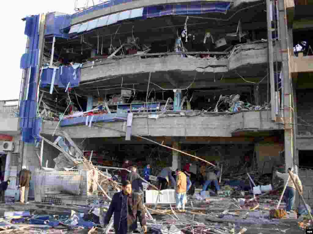 Caption: epa00899200 Iraqis gather in front of a damaged building at the site of a car bomb explosion in Kirkuk north of Baghdad on Wednesday 10 January 2007. A car bomb targeted a commercial center in Kirkuk