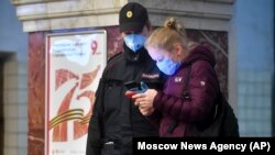 Москва, женщина показывает QR-код для поездки на транспорте полицейскому, 17 апреля 2020 года