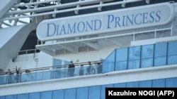 Passengers are seen on the deck of the Diamond Princess cruise ship, with around 3,600 people quarantined onboard due to fears of the new coronavirus, at the Daikaku Pier Cruise Terminal in Yokohama port on February 13, 2020. - At least 218 people on boar