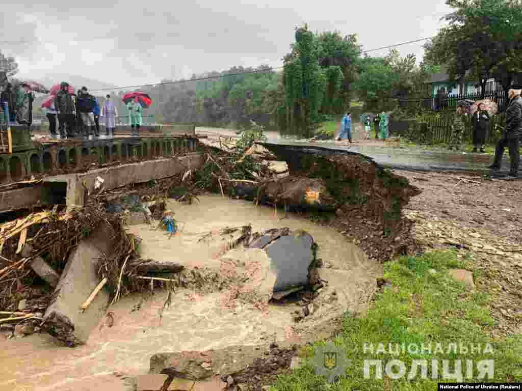 Местные жители стоят на обочине дороги разрушенной потоками воды, Ивано-Франковская область