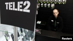 Tele2 операторының дүкенінде тұрған адам.