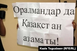 Оралмандар проблемасына арналған жиынға қатысушы ұстап тұрған жазу. Алматы, 4 қазан 2011 жыл. (Көрнекі сурет)