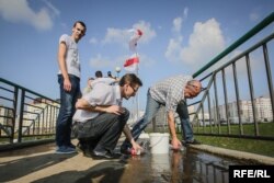 Алесь Лагвінец з чальцамі прыбірае вялікую лужыну з маста, якая замінае хадзіць людзям